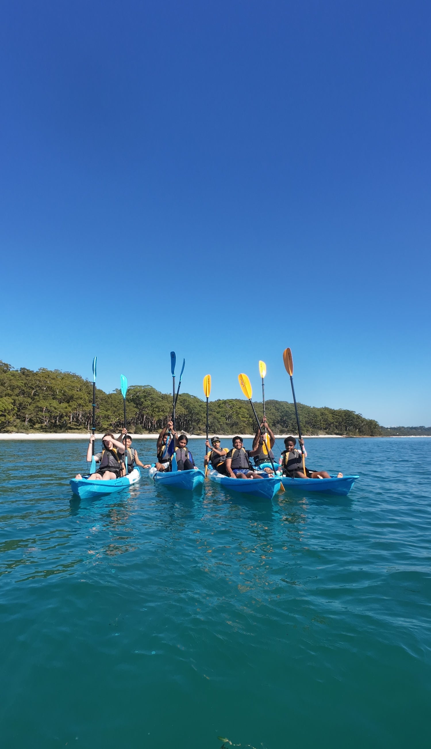 Group of students kayaking on Jervis Bay with Booderee National Park in the background